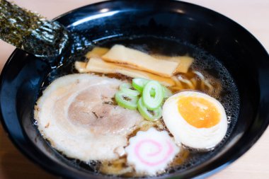 Siyah bardakta soya soslu ramen sosu, üzerine chashu domuz eti, Naruto balık köftesi, soya soslu yumurta turşusu, menma bambu filizleri ve yosun. Ramen kendine özgü bir Japon usulü şehriye çorbası..