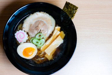 Siyah bardakta soya soslu ramen sosu, üzerine chashu domuz eti, Naruto balık köftesi, soya soslu yumurta turşusu, menma bambu filizleri ve yosun. Ramen kendine özgü bir Japon usulü şehriye çorbası..