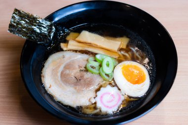 Siyah bardakta soya soslu ramen sosu, üzerine chashu domuz eti, Naruto balık köftesi, soya soslu yumurta turşusu, menma bambu filizleri ve yosun. Ramen kendine özgü bir Japon usulü şehriye çorbası..