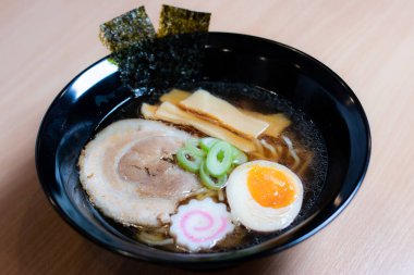 Siyah bardakta soya soslu ramen sosu, üzerine chashu domuz eti, Naruto balık köftesi, soya soslu yumurta turşusu, menma bambu filizleri ve yosun. Ramen kendine özgü bir Japon usulü şehriye çorbası..
