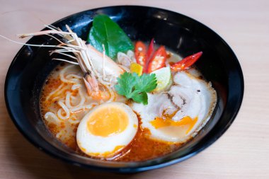 Tom Yum Ramen üzerine chashu domuz eti, soya soslu yumurta turşusu, nehir karidesi ve Tom yum baharatları. Tom Yum Ramen, Taylandlı Tom Yum ile birleşerek lezzetli bir tat veren Japon usulü bir eriştedir..