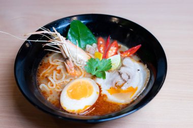 Tom Yum Ramen üzerine chashu domuz eti, soya soslu yumurta turşusu, nehir karidesi ve Tom yum baharatları. Tom Yum Ramen, Taylandlı Tom Yum ile birleşerek lezzetli bir tat veren Japon usulü bir eriştedir..