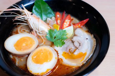 Tom Yum Ramen üzerine chashu domuz eti, soya soslu yumurta turşusu, nehir karidesi ve Tom yum baharatları. Tom Yum Ramen, Taylandlı Tom Yum ile birleşerek lezzetli bir tat veren Japon usulü bir eriştedir..