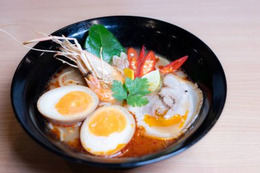Tom Yum Ramen üzerine chashu domuz eti, soya soslu yumurta turşusu, nehir karidesi ve Tom yum baharatları. Tom Yum Ramen, Taylandlı Tom Yum ile birleşerek lezzetli bir tat veren Japon usulü bir eriştedir..