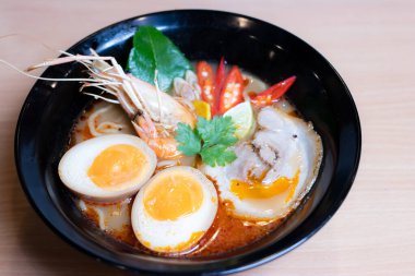 Tom Yum Ramen üzerine chashu domuz eti, soya soslu yumurta turşusu, nehir karidesi ve Tom yum baharatları. Tom Yum Ramen, Taylandlı Tom Yum ile birleşerek lezzetli bir tat veren Japon usulü bir eriştedir..