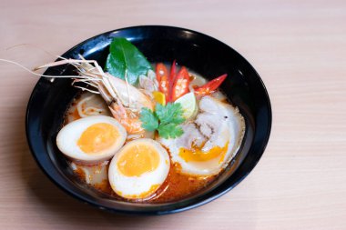 Tom Yum Ramen üzerine chashu domuz eti, soya soslu yumurta turşusu, nehir karidesi ve Tom yum baharatları. Tom Yum Ramen, Taylandlı Tom Yum ile birleşerek lezzetli bir tat veren Japon usulü bir eriştedir..