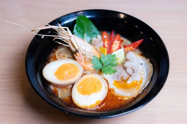 Tom Yum Ramen üzerine chashu domuz eti, soya soslu yumurta turşusu, nehir karidesi ve Tom yum baharatları. Tom Yum Ramen, Taylandlı Tom Yum ile birleşerek lezzetli bir tat veren Japon usulü bir eriştedir..