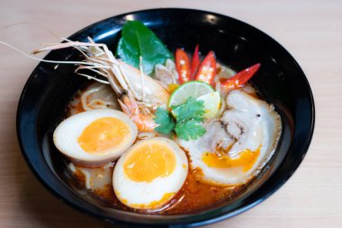 Tom Yum Ramen üzerine chashu domuz eti, soya soslu yumurta turşusu, nehir karidesi ve Tom yum baharatları. Tom Yum Ramen, Taylandlı Tom Yum ile birleşerek lezzetli bir tat veren Japon usulü bir eriştedir..