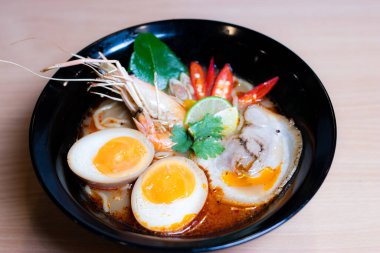 Tom Yum Ramen üzerine chashu domuz eti, soya soslu yumurta turşusu, nehir karidesi ve Tom yum baharatları. Tom Yum Ramen, Taylandlı Tom Yum ile birleşerek lezzetli bir tat veren Japon usulü bir eriştedir..