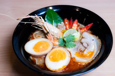 Tom Yum Ramen üzerine chashu domuz eti, soya soslu yumurta turşusu, nehir karidesi ve Tom yum baharatları. Tom Yum Ramen, Taylandlı Tom Yum ile birleşerek lezzetli bir tat veren Japon usulü bir eriştedir..