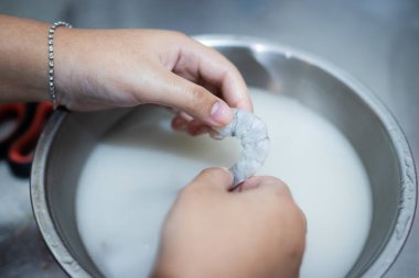 Karidesleri soyan eller, karides kokusunu azaltmak için una batırır..