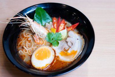 Tom Yum Ramen üzerine chashu domuz eti, soya soslu yumurta turşusu, nehir karidesi ve Tom yum baharatları. Tom Yum Ramen, Taylandlı Tom Yum ile birleşerek lezzetli bir tat veren Japon usulü bir eriştedir..