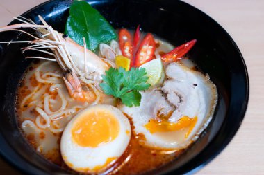 Tom Yum Ramen üzerine chashu domuz eti, soya soslu yumurta turşusu, nehir karidesi ve Tom yum baharatları. Tom Yum Ramen, Taylandlı Tom Yum ile birleşerek lezzetli bir tat veren Japon usulü bir eriştedir..