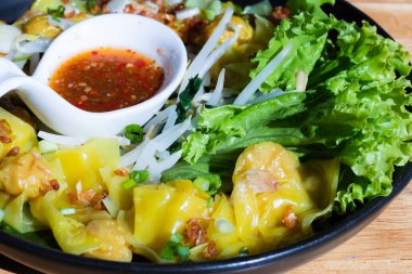 Yeşil marullu ve soslu bir kasede domuz etli börek.