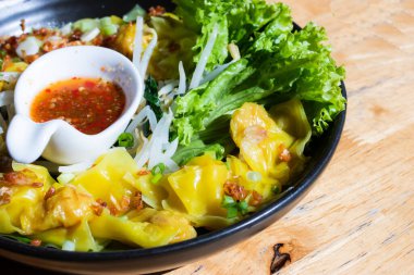 Yeşil marullu ve soslu bir kasede domuz etli börek.