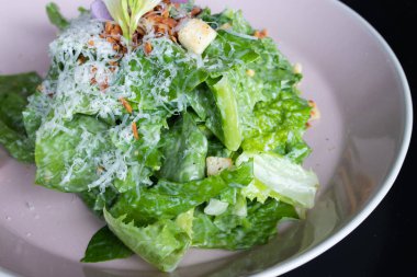 Siyah arkaplanlı bir tabakta çeşitli sebze salatası çeşitleri