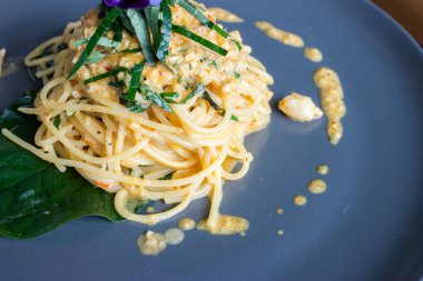 Füzyon spagettisi ve yengeç eti Tayland usulü mavi tabakta pişirildi.