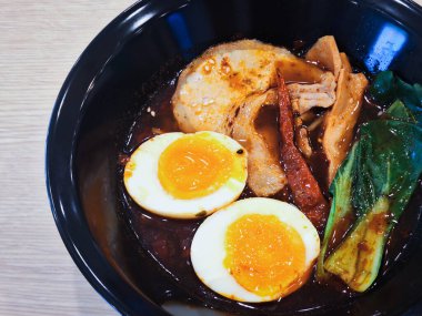 Chashu domuz eti, soya soslu yumurta turşusu, menma bambu filizleri ile kaplanmış siyah bir fincanda Mala Ramen Japon ve Çin tarzı eriştenin eritilmiş halidir..