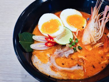 Tom Yum Ramen üzerine chashu domuz eti, soya soslu yumurta turşusu, nehir karidesi ve Tom yum baharatları. Tom Yum Ramen, Taylandlı Tom Yum ile birleşerek lezzetli bir tat veren Japon usulü bir eriştedir..