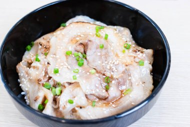 Donburi pilavı, siyah bir kasede domuz dilimleri ile kaplanmış..