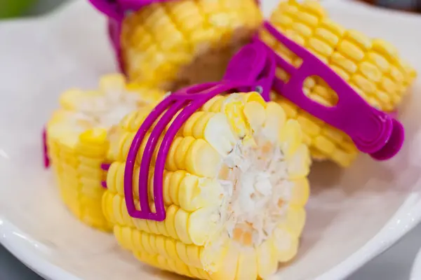 stock image Fresh sweet corn cut into sections and clamped with a purple stick.