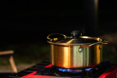 Pirinç tencere, çorba kaynatmak için piknik sobasına konur..