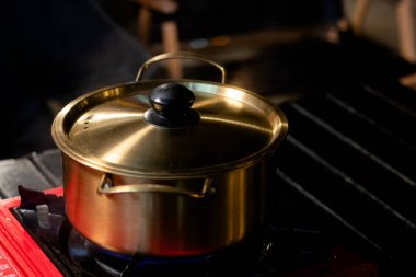 Pirinç tencere, çorba kaynatmak için piknik sobasına konur..