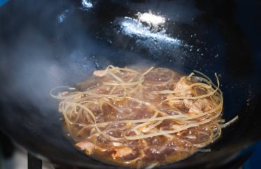 Aşçı Pad Mee Korat, Tavada Kızarmış Erişte Tayland usulü. Sokak yemekleri konsepti.