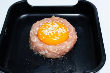 Shabu olarak servis etmek için siyah tepside yumurta sarısı ile kaplı çiğ domuz eti..