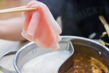 Shabu Shabu ve Sukiyaki. Yemek çubukları dilimlenmiş et çubukları, yemek çubukları ve sıcak tencere arkası..