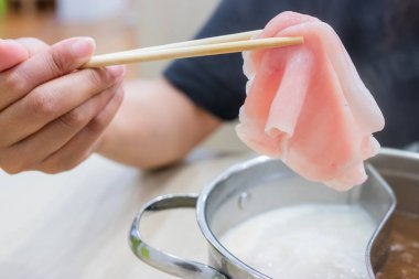 Shabu Shabu ve Sukiyaki. Yemek çubukları dilimlenmiş et çubukları, yemek çubukları ve sıcak tencere arkası..