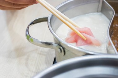 Shabu Shabu ve Sukiyaki. Yemek çubukları dilimlenmiş et çubukları, yemek çubukları ve sıcak tencere arkası..
