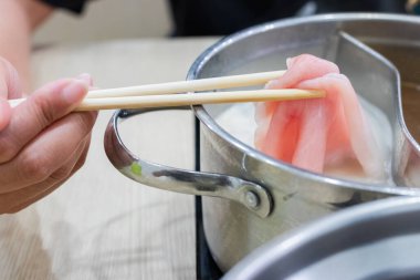 Shabu Shabu ve Sukiyaki. Yemek çubukları dilimlenmiş et çubukları, yemek çubukları ve sıcak tencere arkası..