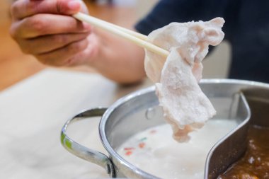 Shabu Shabu ve Sukiyaki. Yemek çubukları dilimlenmiş et çubukları, yemek çubukları ve sıcak tencere arkası..