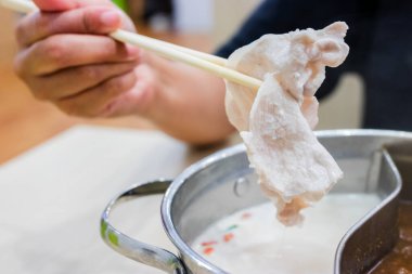 Shabu Shabu ve Sukiyaki. Yemek çubukları dilimlenmiş et çubukları, yemek çubukları ve sıcak tencere arkası..
