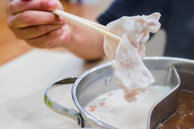Shabu Shabu ve Sukiyaki. Yemek çubukları dilimlenmiş et çubukları, yemek çubukları ve sıcak tencere arkası..