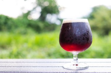 Yeşil doğal arka planda bir bardak el yapımı bira.