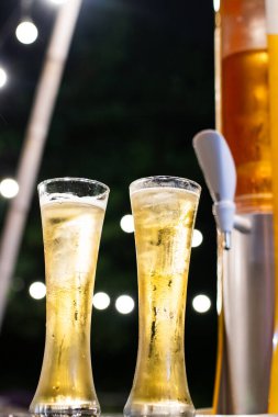 Bir bardak bira kulesi ve bulanık altın sarısı bir bokeh. Restoranda dinlenme zamanı..