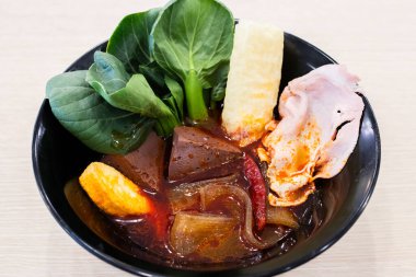 İçinde domuz kanı küpleri, yapraklı yeşiller, acı biber, dilimlenmiş domuz pastası, balık keki ve kızarmış tofu derisi olan canlı bir Asya çorbası. Acı biber yağıyla bezenmiş zengin kırmızı et suyu taze sebzelerle ve çeşitli sebzelerle çok güzel tezat oluşturuyor.