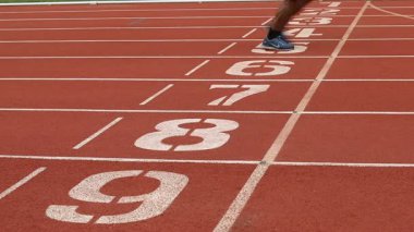 İnsanlar stadyumdaki kırmızı koşu bandında ya da atletizm pistinde koşuyorlar..