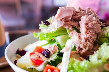 Marul, vişneli domates, dolmalık biber, ananas, badem ve soslu taze ton balığı salatası. Diyet, beslenme ve gıda reklamları için mükemmel renkli ve sağlıklı bir yemek..