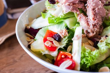 Marul, vişneli domates, dolmalık biber, ananas, badem ve soslu taze ton balığı salatası. Diyet, beslenme ve gıda reklamları için mükemmel renkli ve sağlıklı bir yemek..