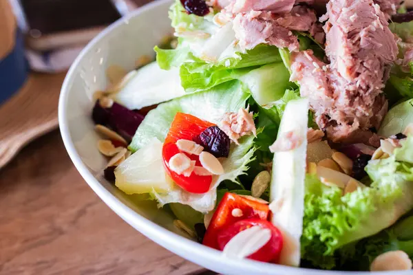 Marul, vişneli domates, dolmalık biber, ananas, badem ve soslu taze ton balığı salatası. Diyet, beslenme ve gıda reklamları için mükemmel renkli ve sağlıklı bir yemek..