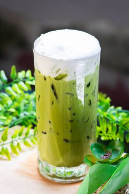 Yeşil yapraklarla çevrili, kremalı süt köpüğüyle kaplı buzlu kibrit yeşil çay, ferahlatıcı ve soğuk..