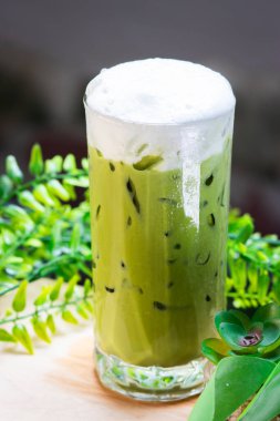 Yeşil yapraklarla çevrili, kremalı süt köpüğüyle kaplı buzlu kibrit yeşil çay, ferahlatıcı ve soğuk..