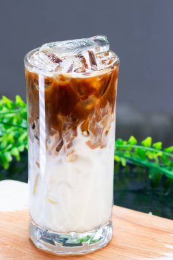 Buzlu sütün üzerine taze demlenmiş espresso dökülüyor. Büyük bir bardakta. Görünür süt ve buz tabakalarıyla güzel bir buzlu latte yaratıyor..