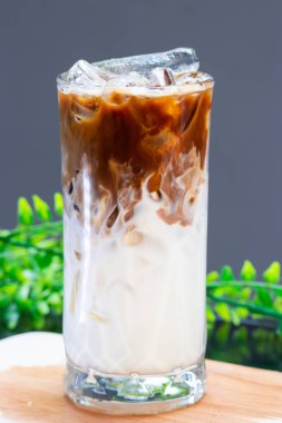 Buzlu sütün üzerine taze demlenmiş espresso dökülüyor. Büyük bir bardakta. Görünür süt ve buz tabakalarıyla güzel bir buzlu latte yaratıyor..