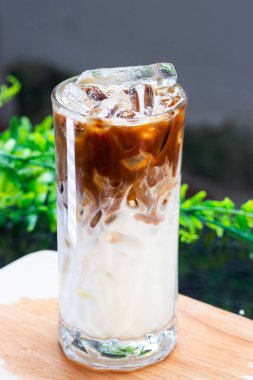 Buzlu sütün üzerine taze demlenmiş espresso dökülüyor. Büyük bir bardakta. Görünür süt ve buz tabakalarıyla güzel bir buzlu latte yaratıyor..