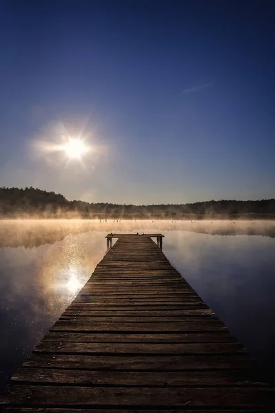 Beautiful summer morning landscape. Wooden pier on the lake shore in the misty morning scenery. Photo taken in Michala Gora, Poland.