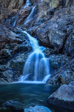 Bulanık su efektli güzel bir şelale. Fotoğraf Polonya Tatra Dağları 'ndaki Beş Göl Vadisi' nde çekildi. Uzun pozlama fotoğrafı.